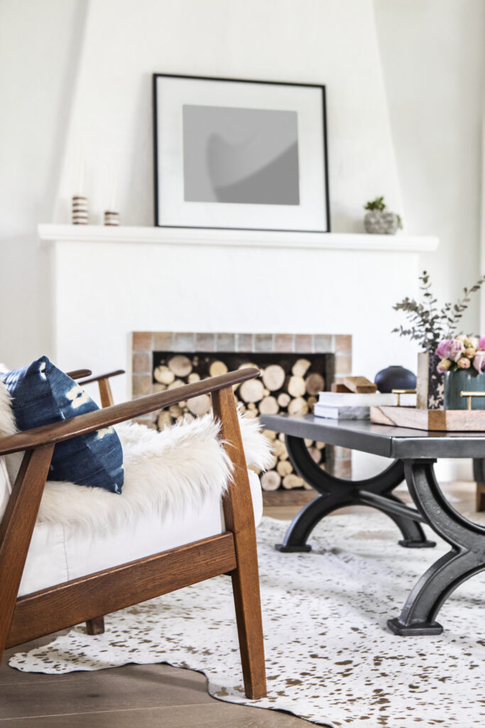 Puinen nojatuoli ja valkoinen takka tyylikkäästi sisustetussa olohuoneessa.